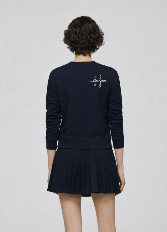 Woman wearing a french navy blue Northwind sweatshirt with Northwind crossword Antwerp Paris embroidered logo on the back, navy skirt