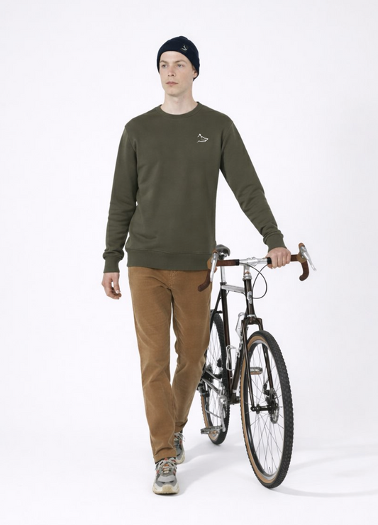 Man wearing a khaki green Northwind sweatshirt with white embroidered Northwind wolf logo on the chest, having bike
