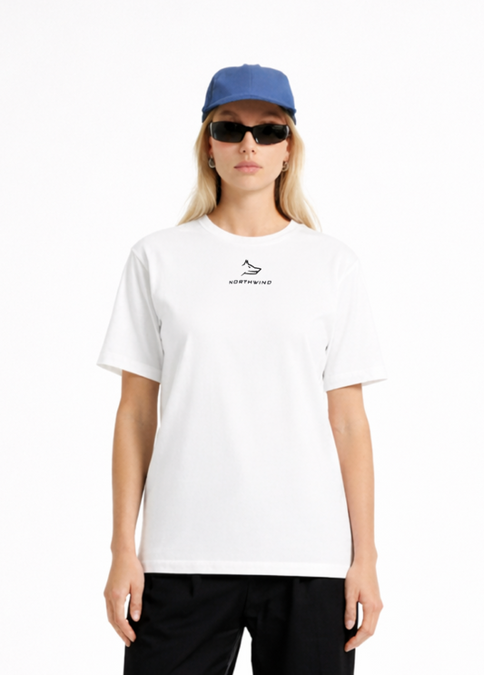 Woman wearing a white Northwind casual t-shirt with minimalist Northwind embroidered wolf logo on the chest, blue hat, black sunglasses and black pants on a white background