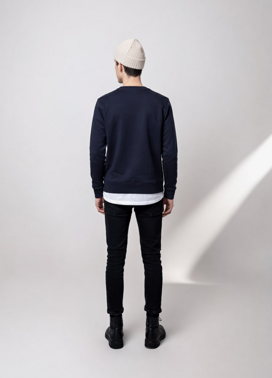 Person wearing a navy blue Northwind lone wolf sweatshirt, black jeans, and a sand cream organic beanie, back pose