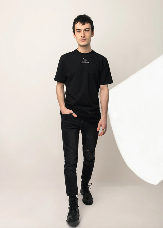 Person wearing a black t-shirt with a logo and black jeans on a white background