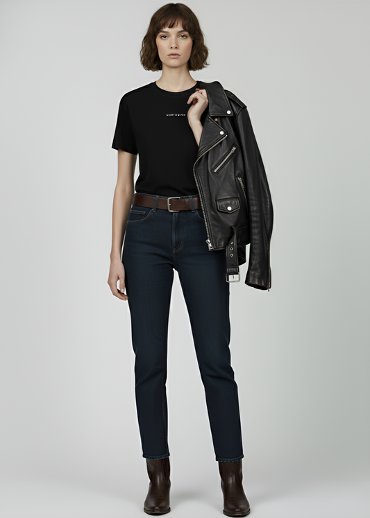 Person wearing a black leather jacket, black Northwind storm of wolves t-shirt, dark jeans, and brown boots on a white background