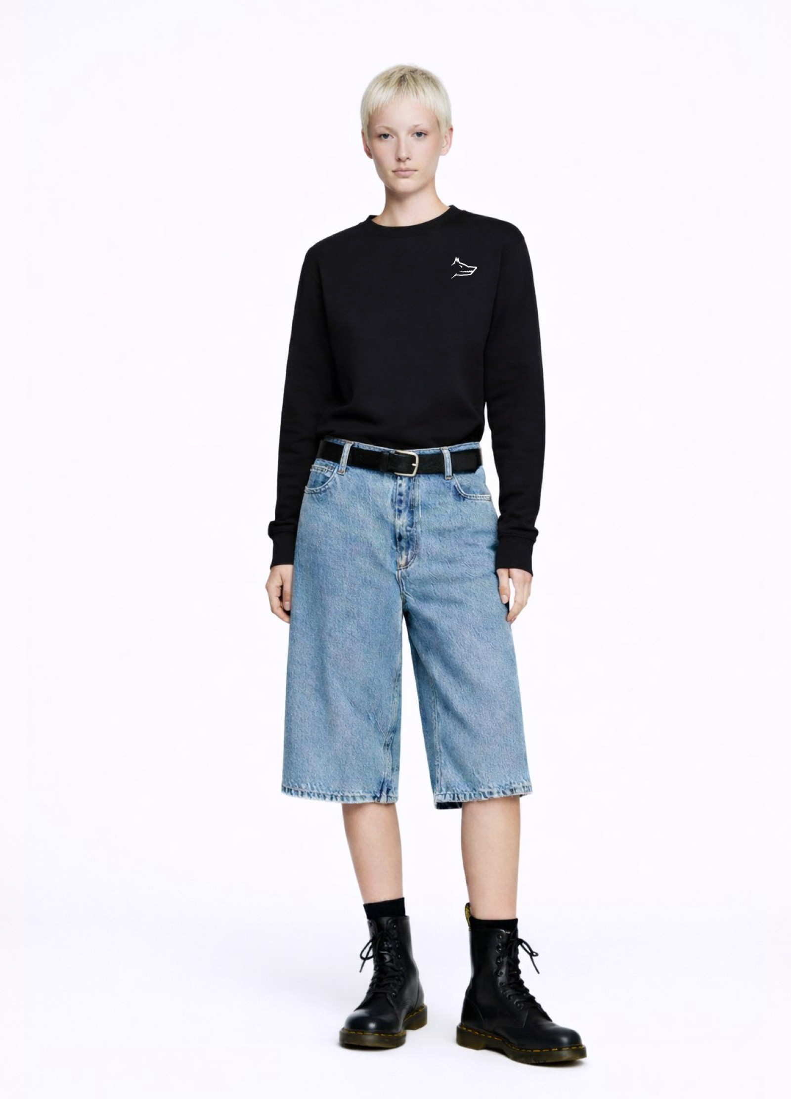 Woman wearing a black Northwind Crossword sweatshirt with Northwind wolf embroidered logo on the chest, white shirt, blue jeans, and black Dr Martens boots