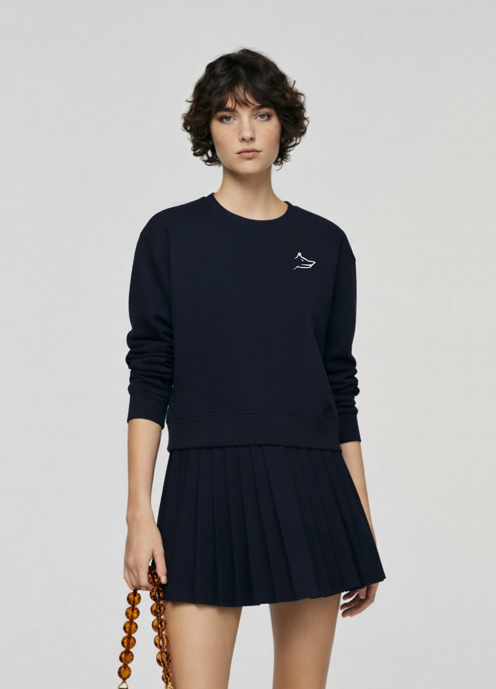 Woman wearing a french navy blue Northwind sweatshirt with Northwind wolf embroidered logo on the chest, navy skirt, and leather bobbies shoes with mid-heeled slingback pointed-toe pumps