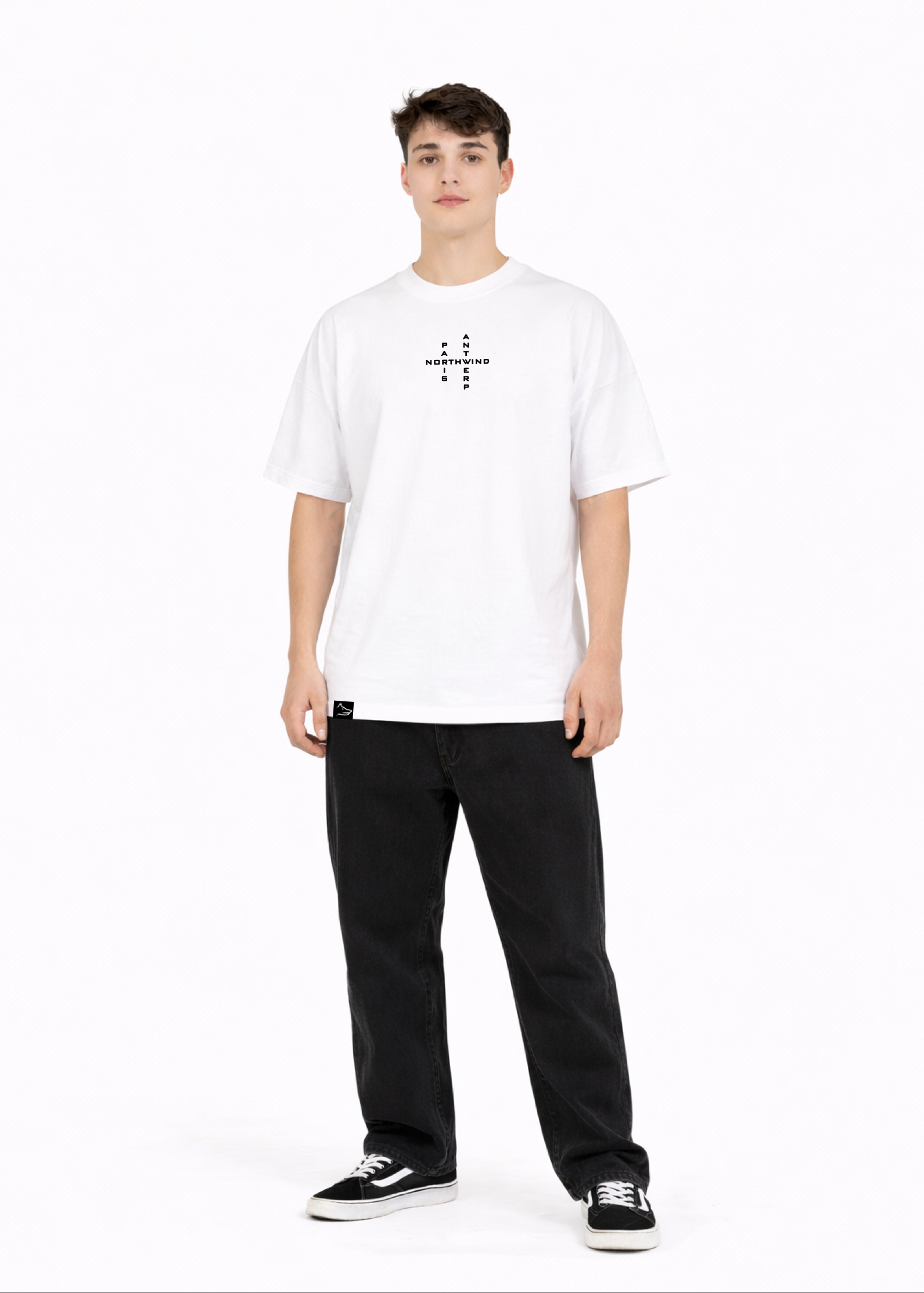Young adult wearing a Northwind oversized organic cotton white t-shirt with Northwind crossword ANTWERP and PARIS logo embroidered on the chest, Carhartt pants, black Vans shoes
