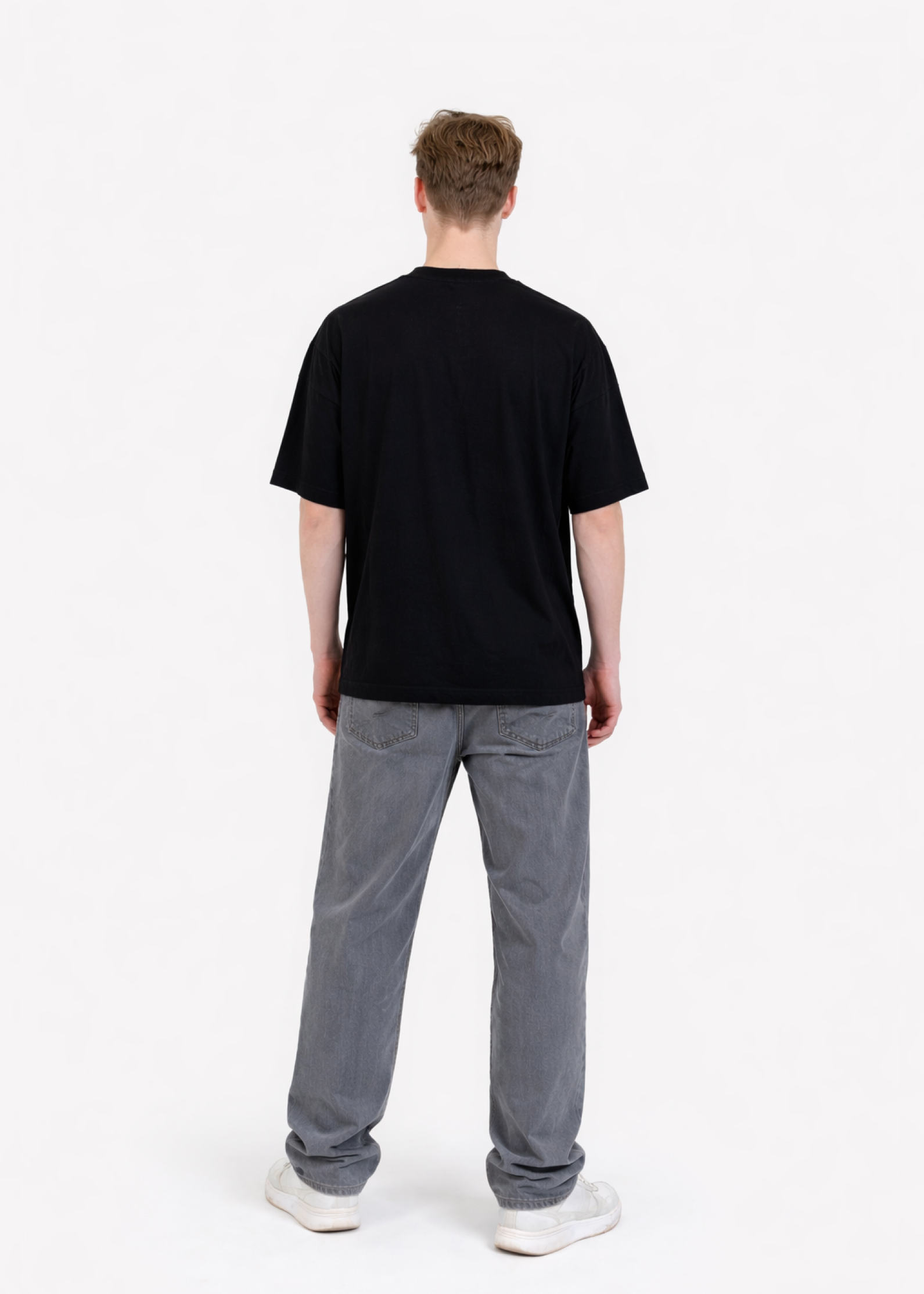 Person wearing a black organic cotton oversized t-shirt and gray pants on a white background