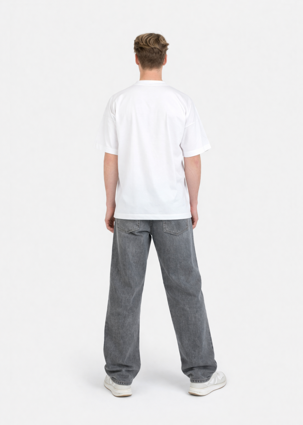 Person wearing a white organic cotton oversized Northwind t-shirt and gray jeans on a white background
