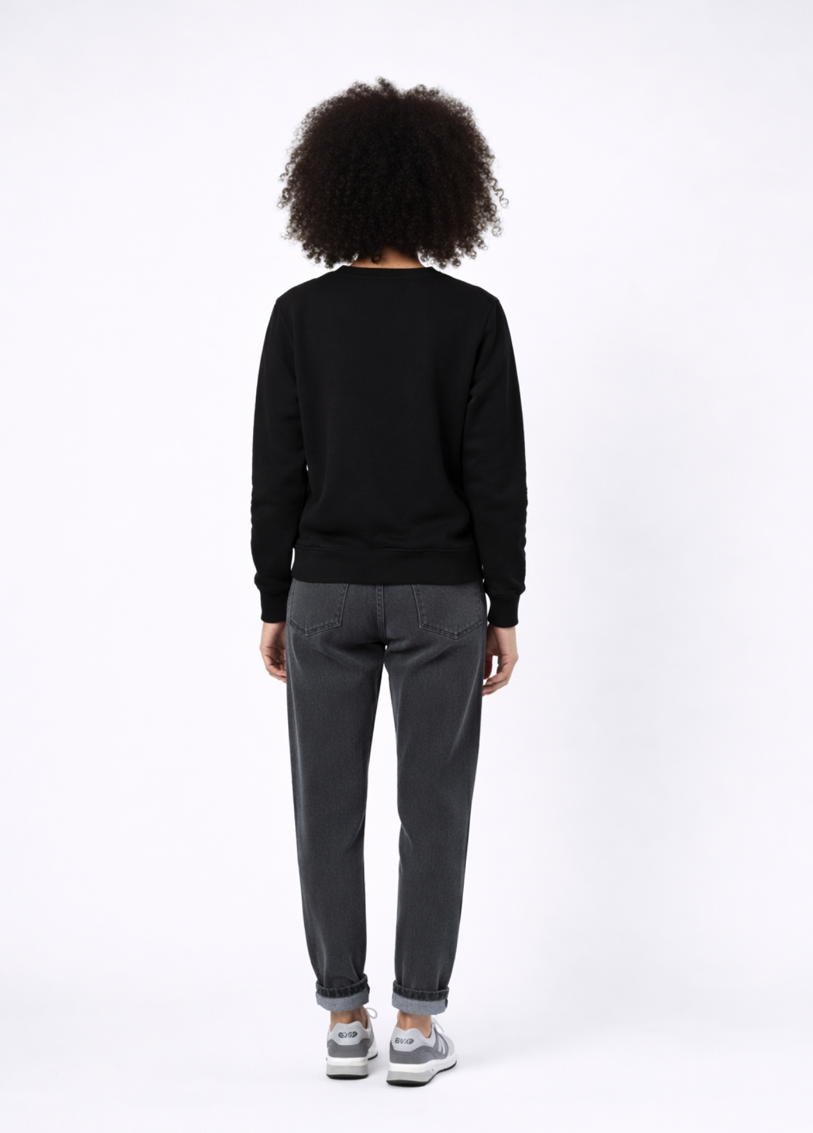 Woman wearing Northwind lone Wolf black sweatshirt, gray levis jean and New Balance shoes