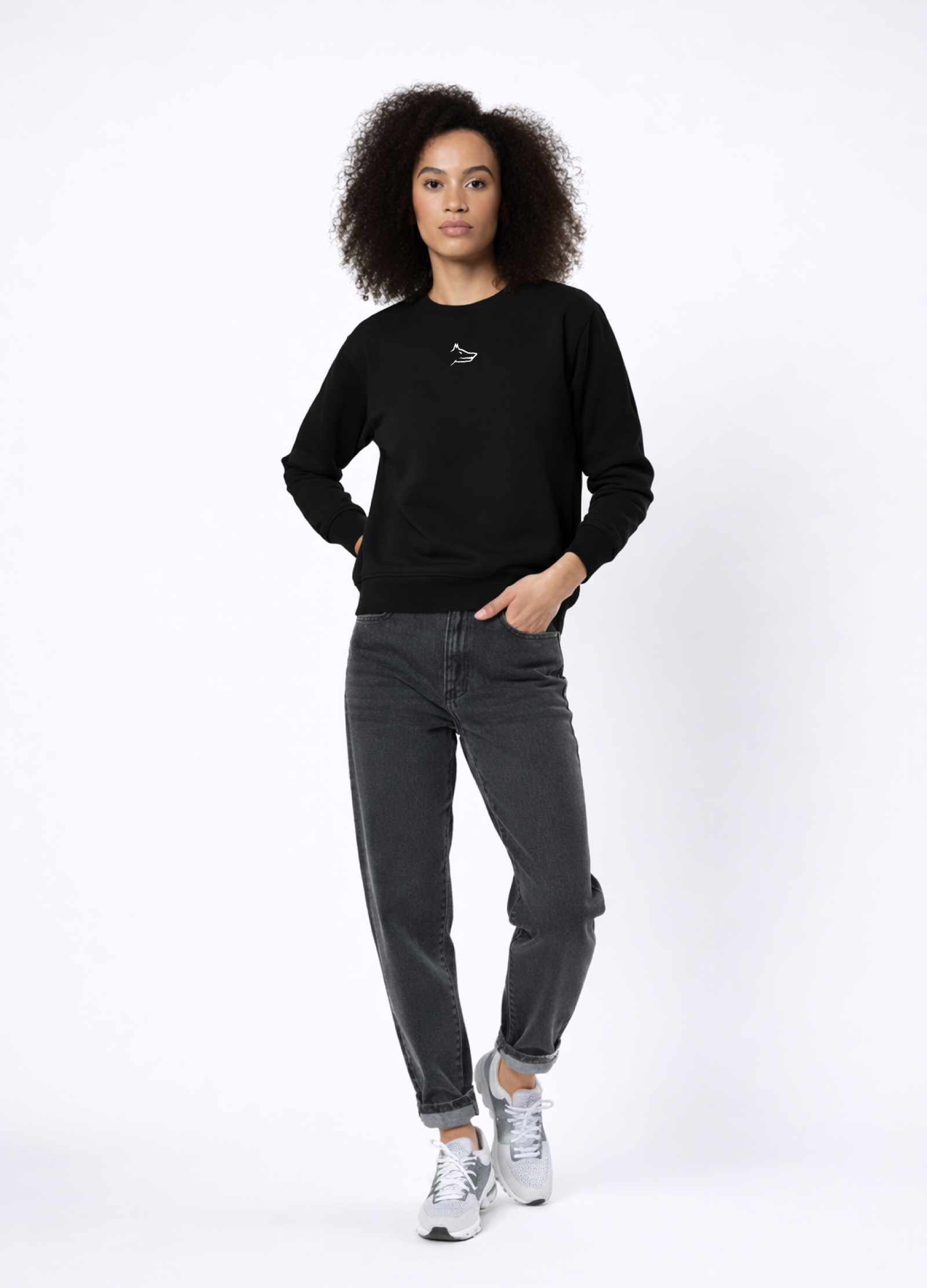 Woman wearing Northwind Lone Wolf black sweatshirt with wolf logo embroidered on the chest, gray levis jean and New Balance shoes