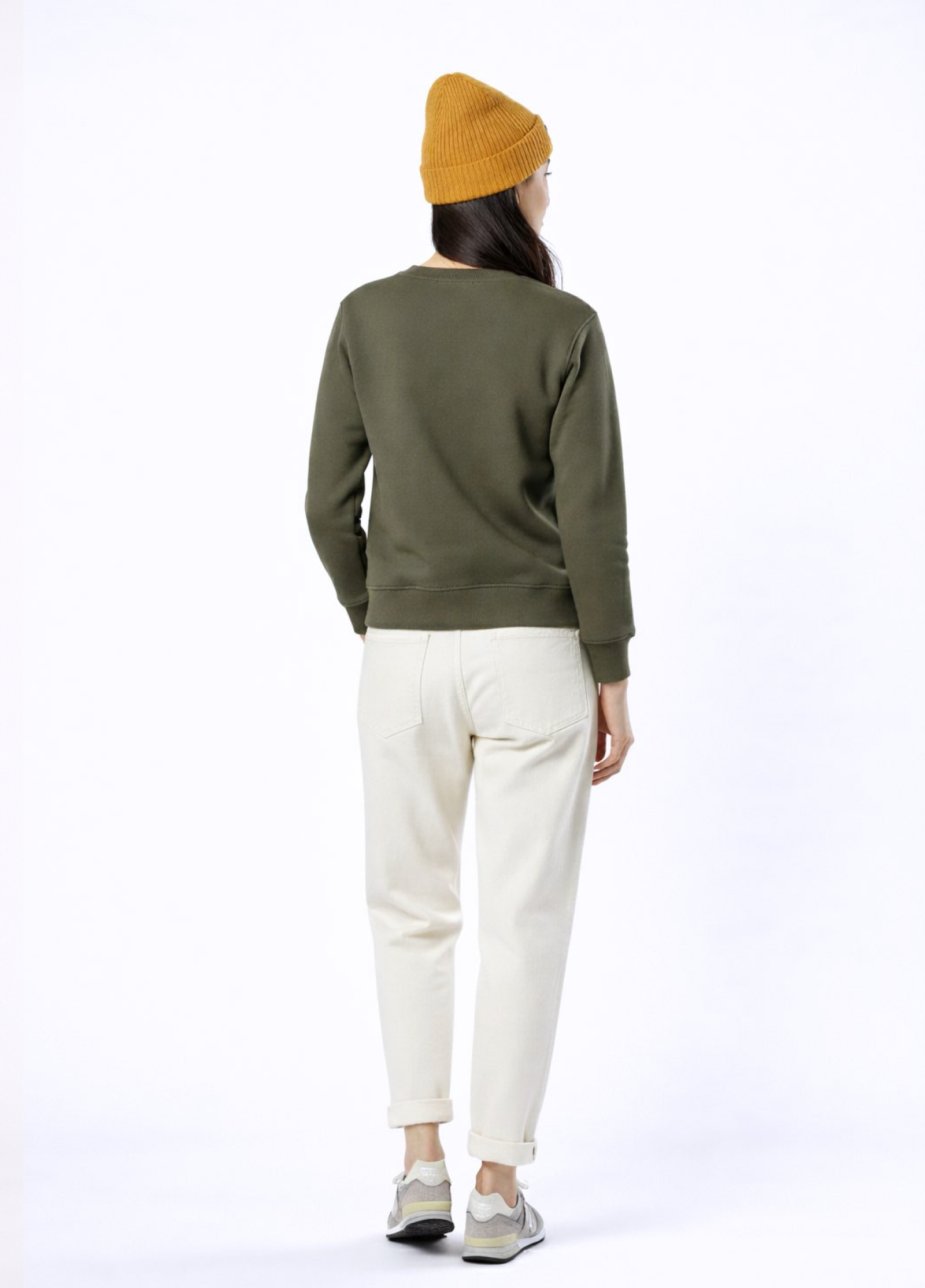 A woman wearing a khaki green Northwind lone wolf sweatshirt, Northwind organic mustard beanie 