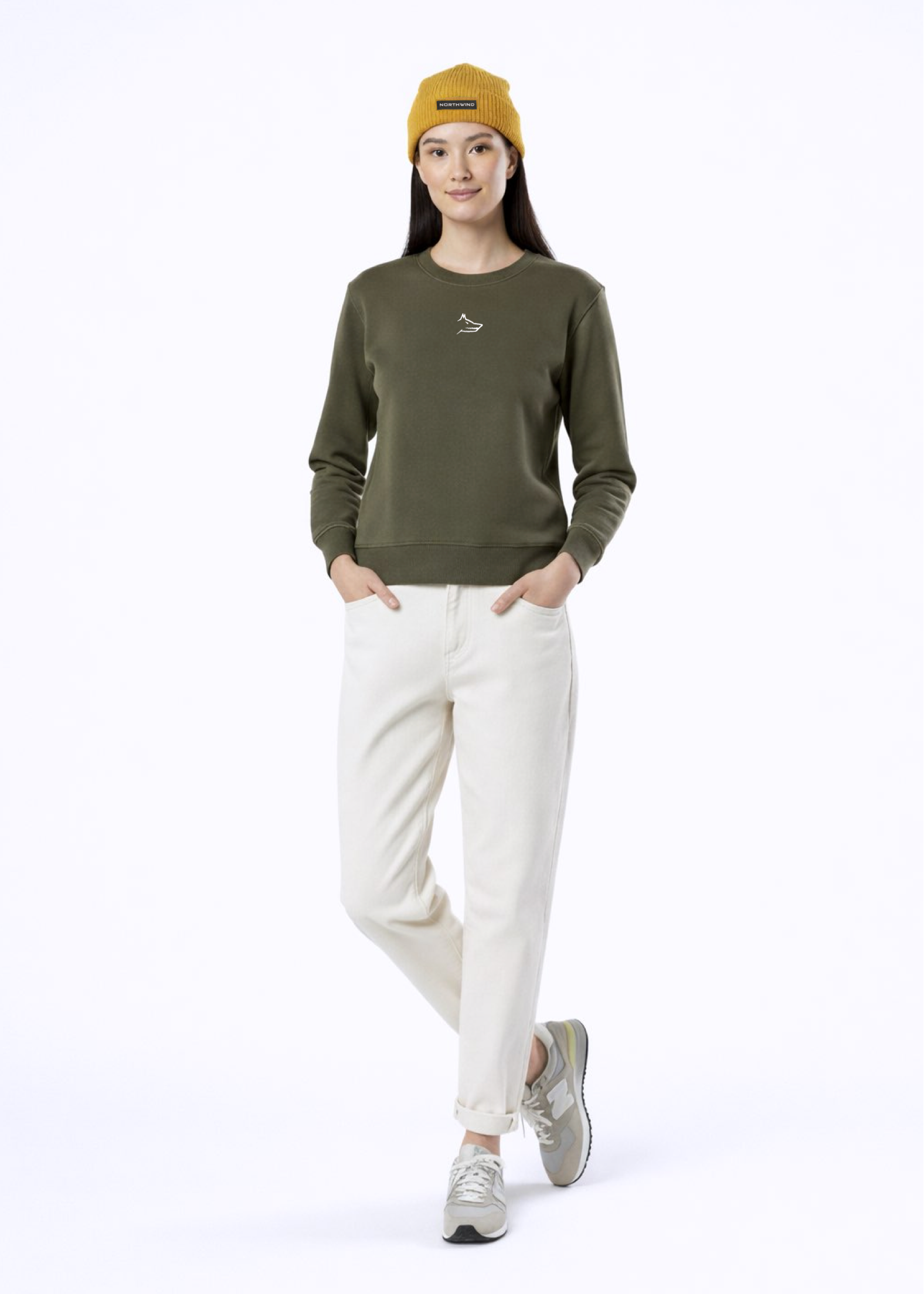 A woman wearing a khaki green Northwind Lone wolf sweatshirt with Northwind wolf embroidered logo on the chest, Northwind organic mustard beanie