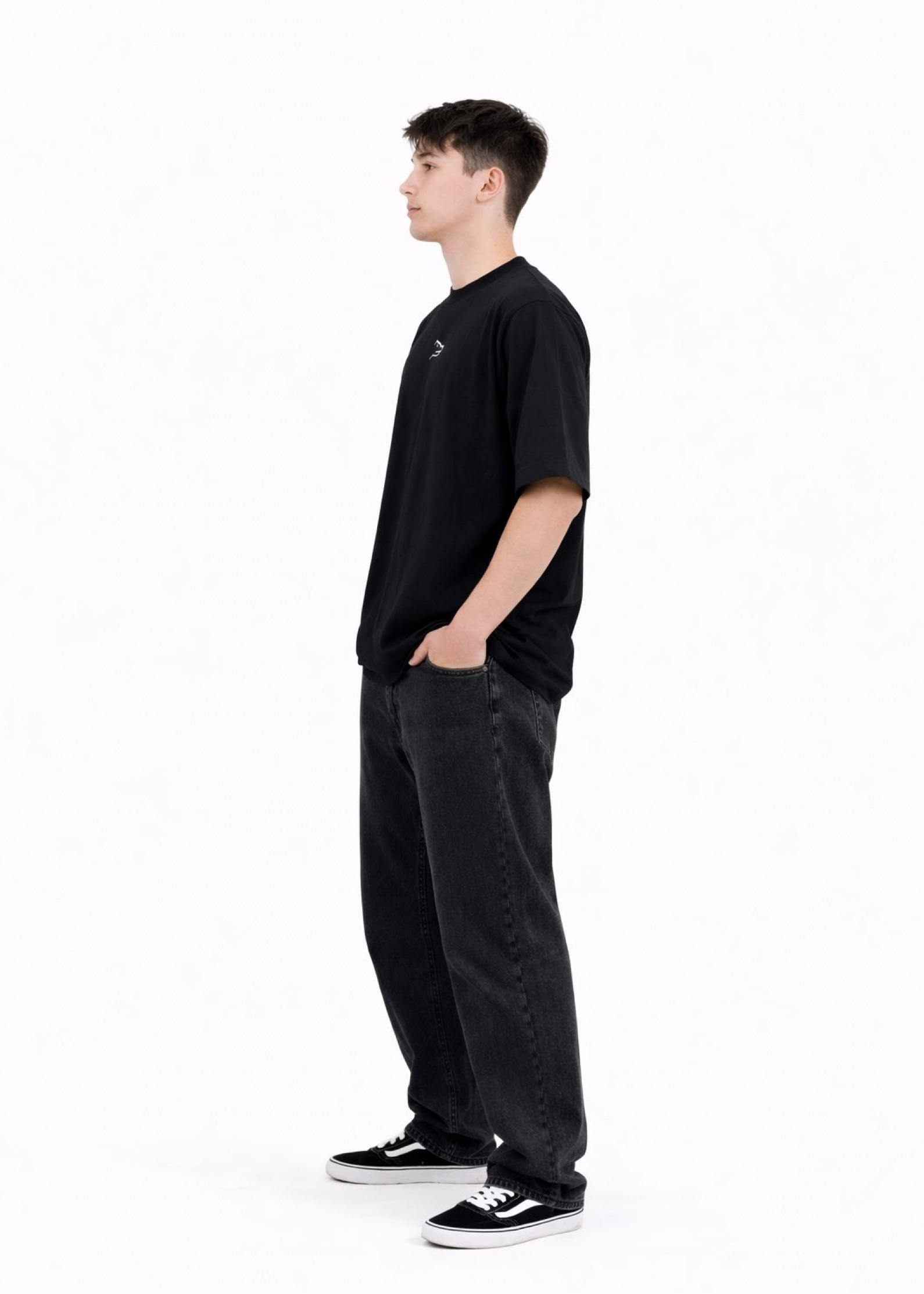 Young adult wearing a Northwind oversized organic cotton black t-shirt with Northwind wolf logo embroidered on the chest, Carhartt pants, black Vans shoes