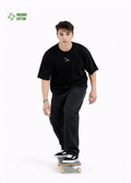 Young adult wearing a Northwind oversized organic cotton black t-shirt with Northwind wolf logo embroidered on the chest, Carhartt pants, black Vans shoes, skating
