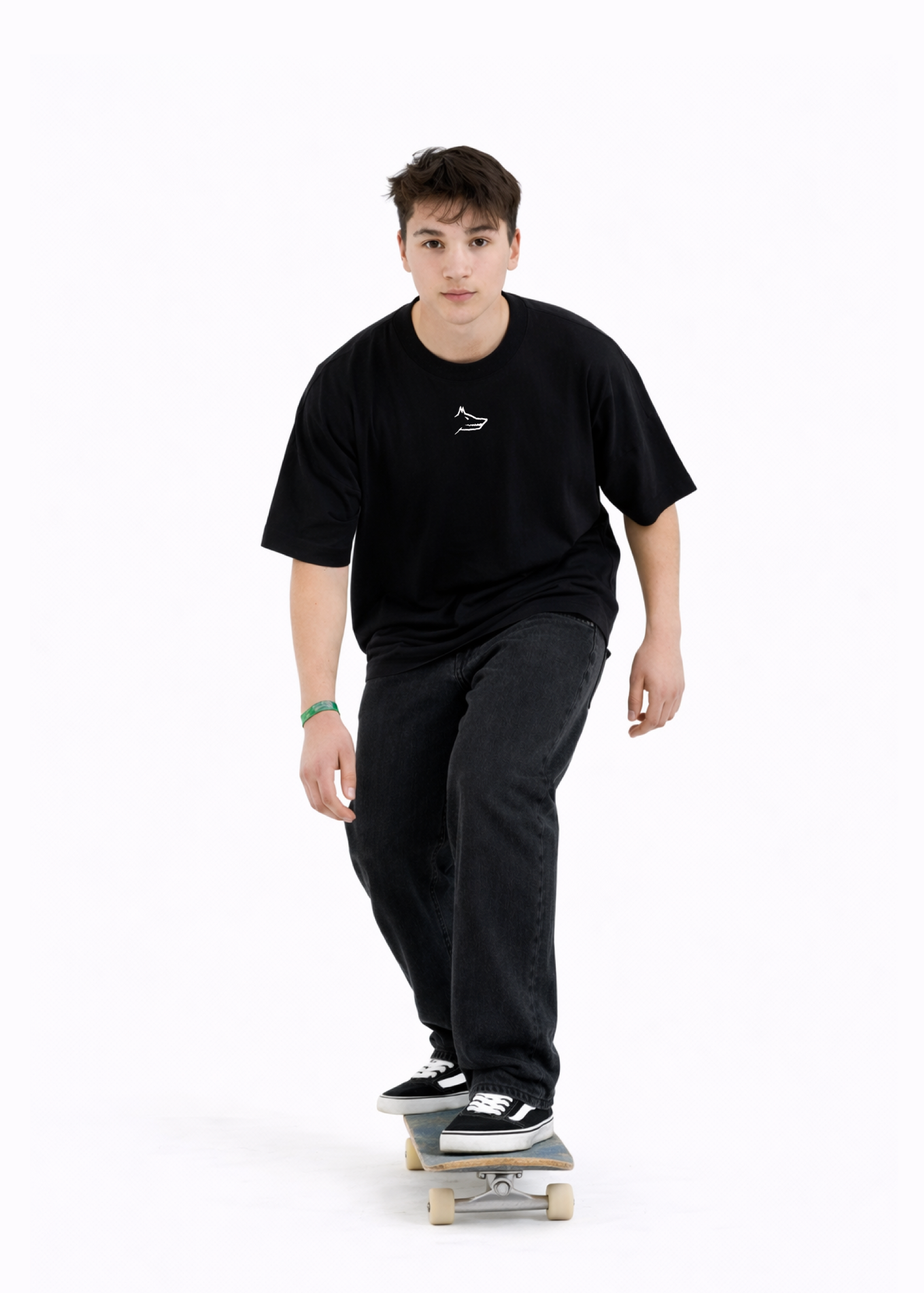 Young adult wearing a Northwind oversized organic cotton black t-shirt with Northwind wolf logo embroidered on the chest, Carhartt pants, black Vans shoes, skating