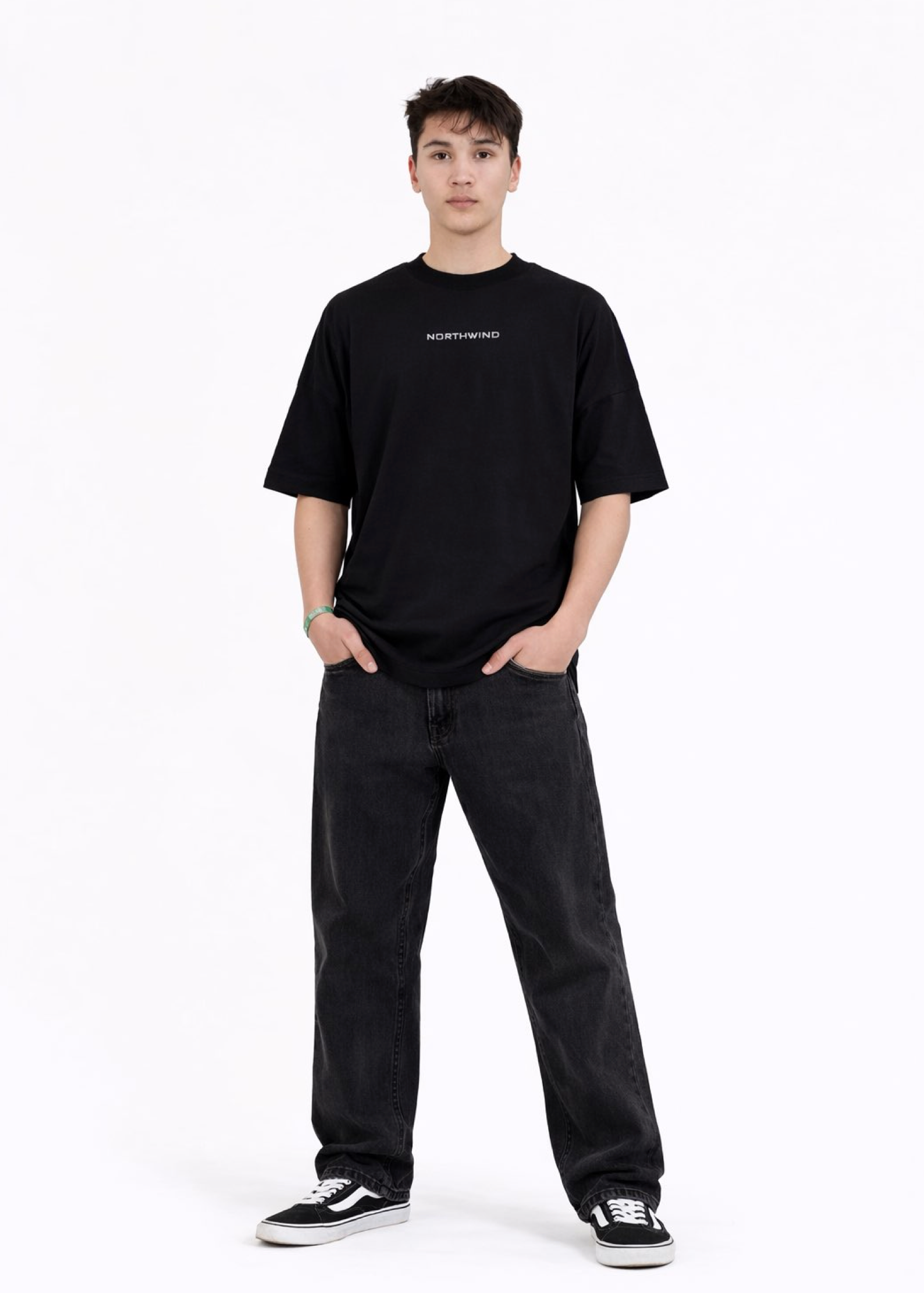 Young adult wearing a Northwind oversized organic cotton black t-shirt with Northwind embroidered on the chest, Carhartt pants, black Vans shoes