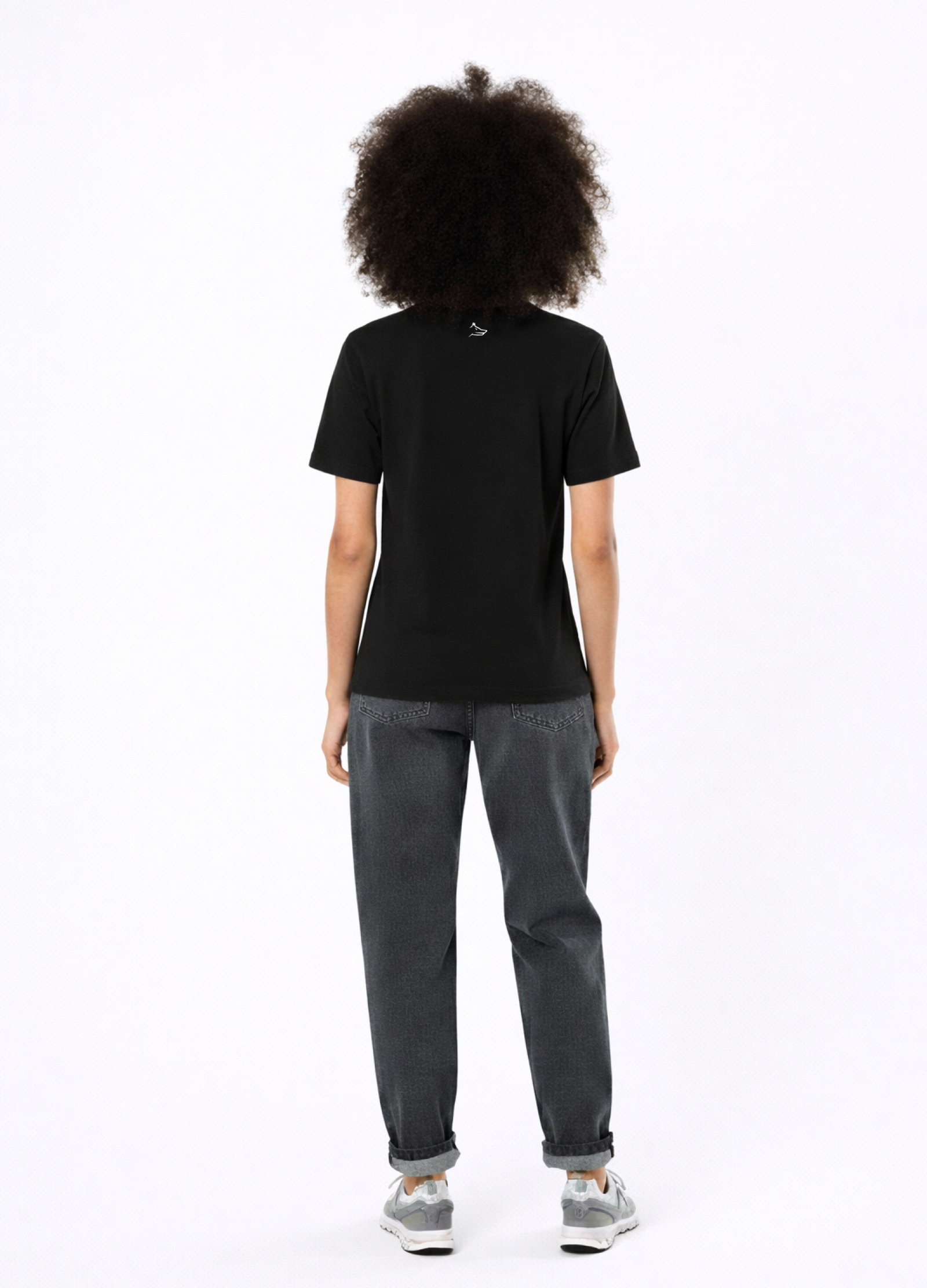 Woman wearing a black Northwind casual t-shirt with minimalist Northwind embroidered logo on the chest and Northwind wolf logo at the back, gray new balance sport shoes