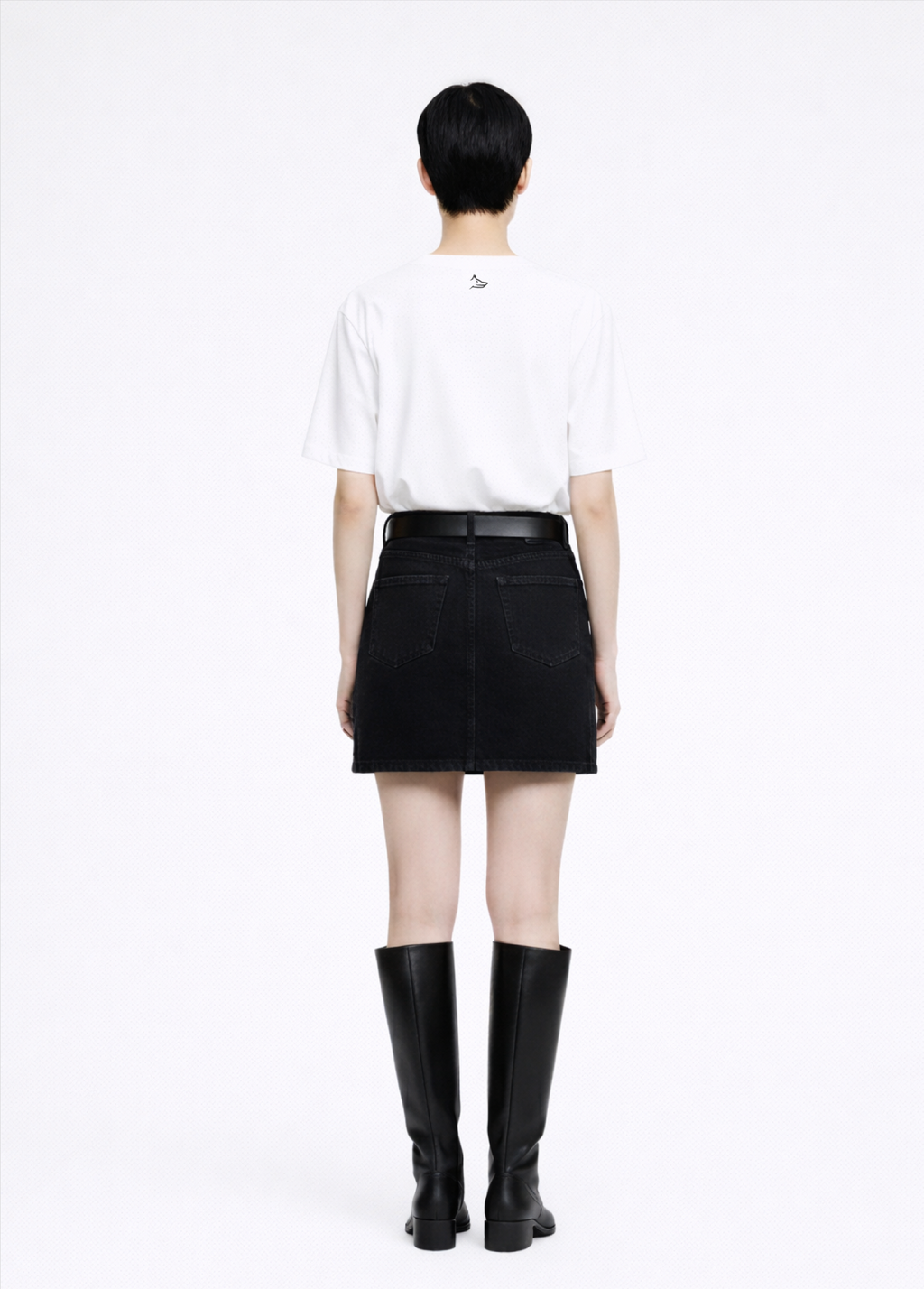 Woman wearing a white Northwind casual t-shirt with minimalist Northwind embroidered wolf logo at the back, black skirt, and black knee-high dr martens boots on a white background