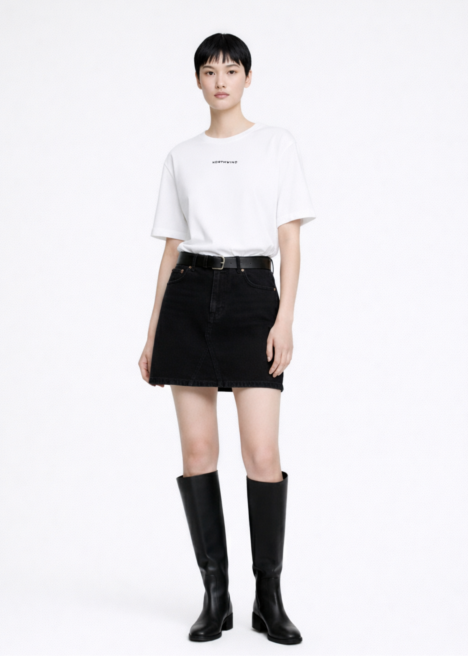 Woman wearing a white Northwind casual t-shirt with minimalist Northwind embroidered wolf logo at the back and black skirt on a white background
