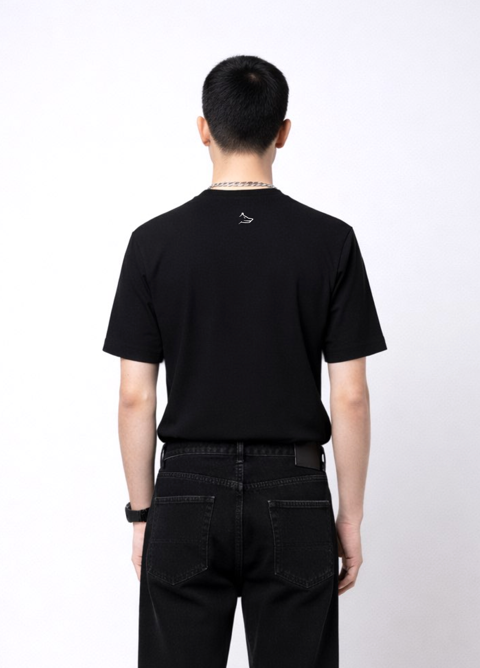 Person wearing an essential northwind black t-shirt with minimalist Northwind embroidered wolf logo on the back and Carhartt black pants on a white background