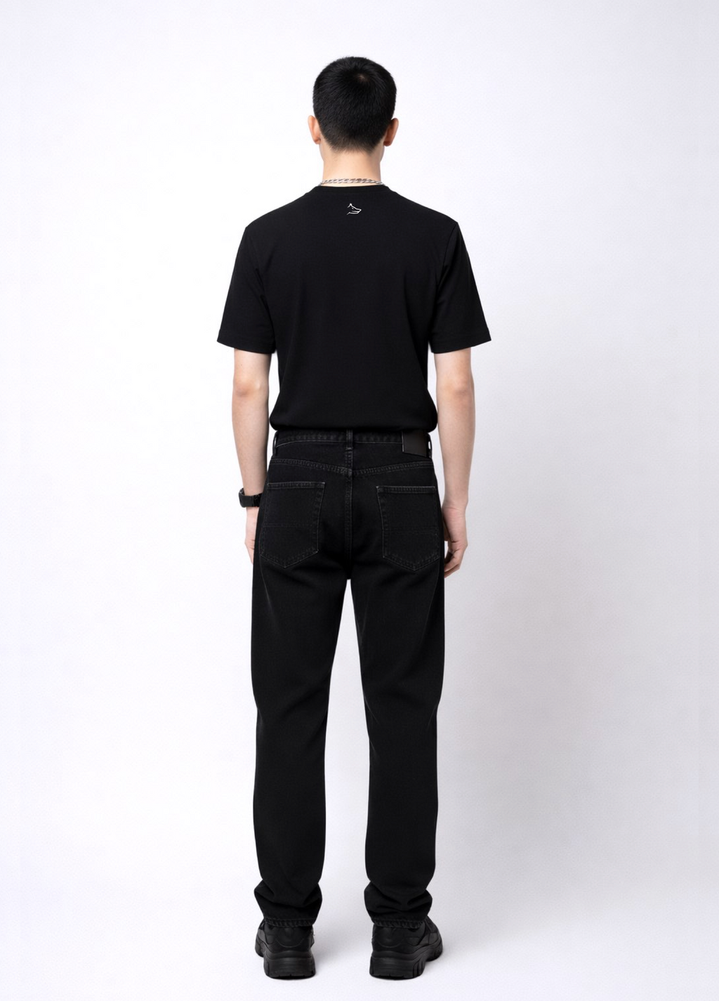 Man wearing an essential Northwind black t-shirt with minimalist Northwind embroidered wolf logo on the back, Dr. Martens boots, Carhartt black pants