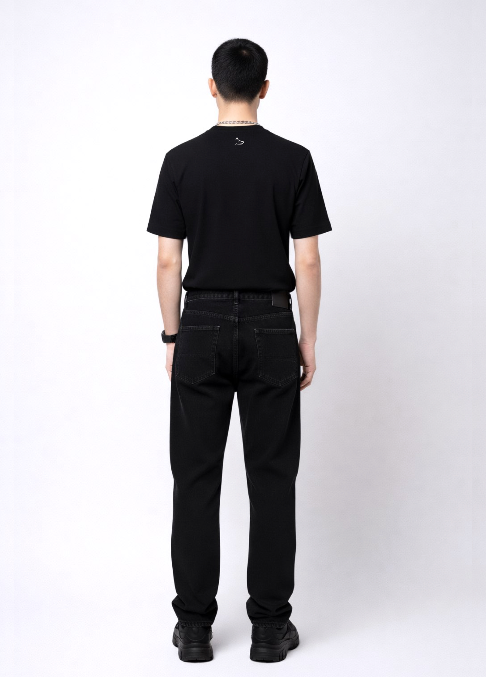 Man wearing an essential Northwind black t-shirt with minimalist Northwind embroidered wolf logo on the back, Dr. Martens boots, Carhartt black pants