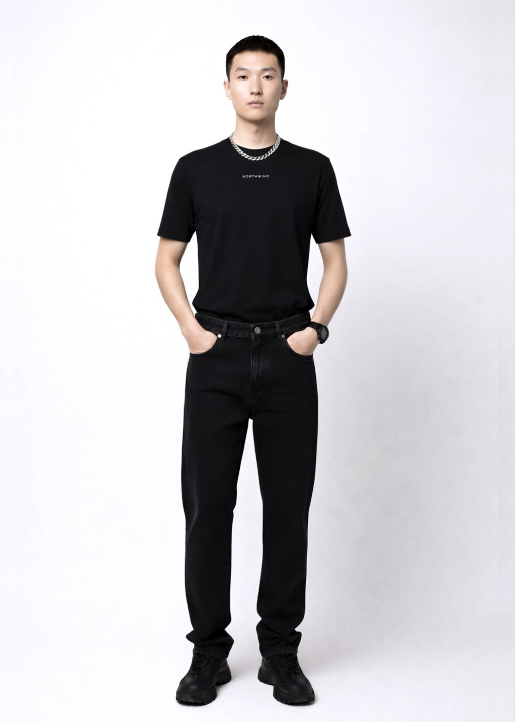 Man wearing an essential Northwind black t-shirt with minimalist Northwind embroidered logo on the chest, Dr. Martens boots, Carhartt black pants and Rolex black watch