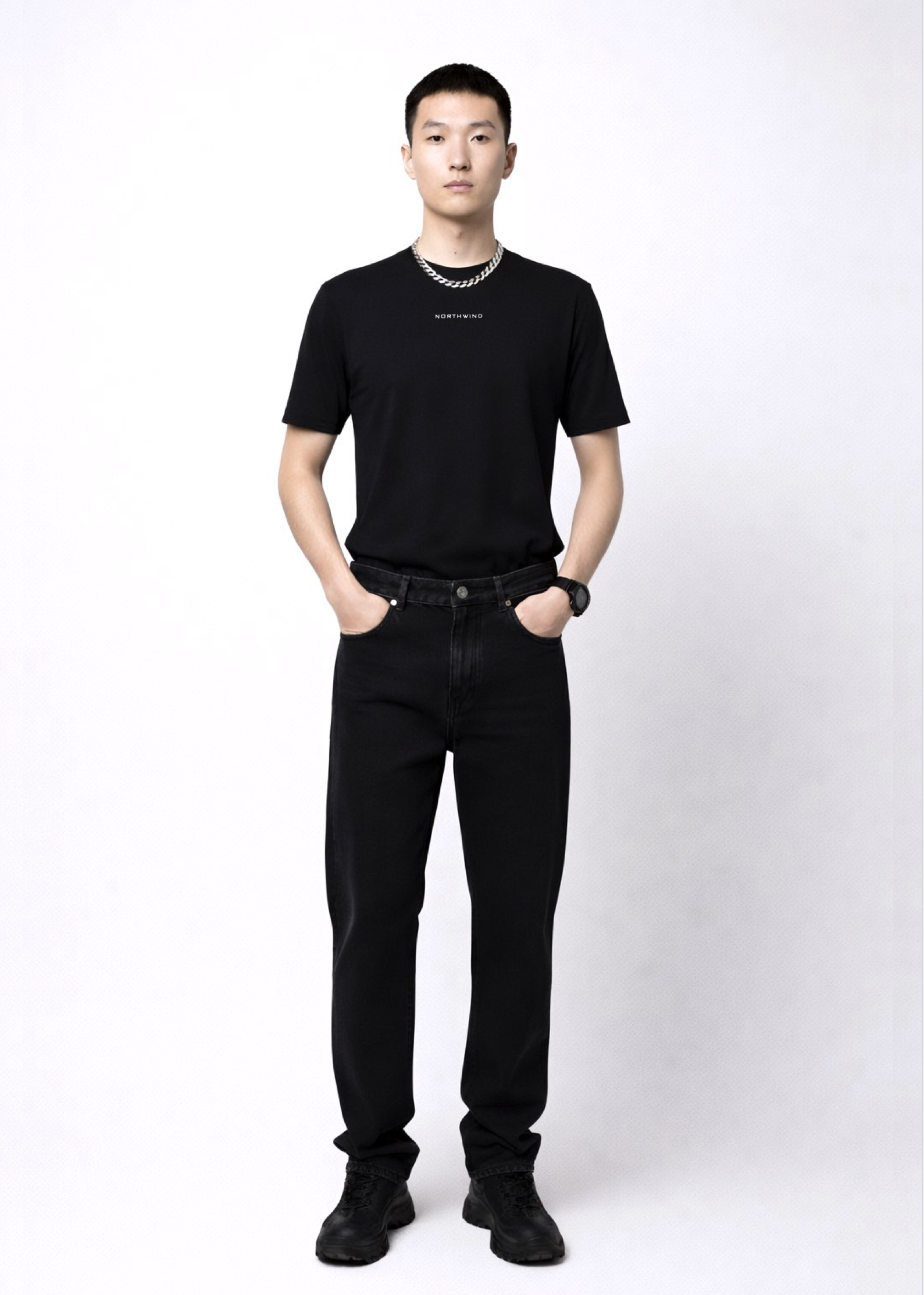 Man wearing an essential Northwind black t-shirt with minimalist Northwind embroidered logo on the chest, Dr. Martens boots, Carhartt black pants and Rolex black watch