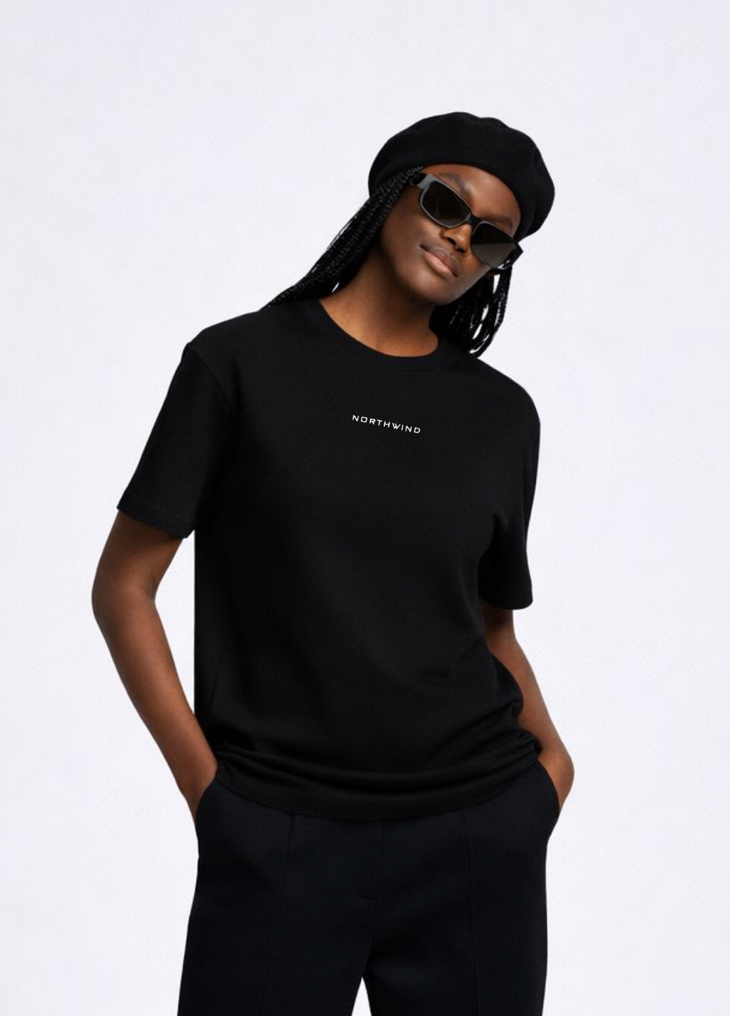 Black woman wearing a black essential Northwind t-shirt with embroidered logo on the chest, Gucci sunglasses and black beret. 
