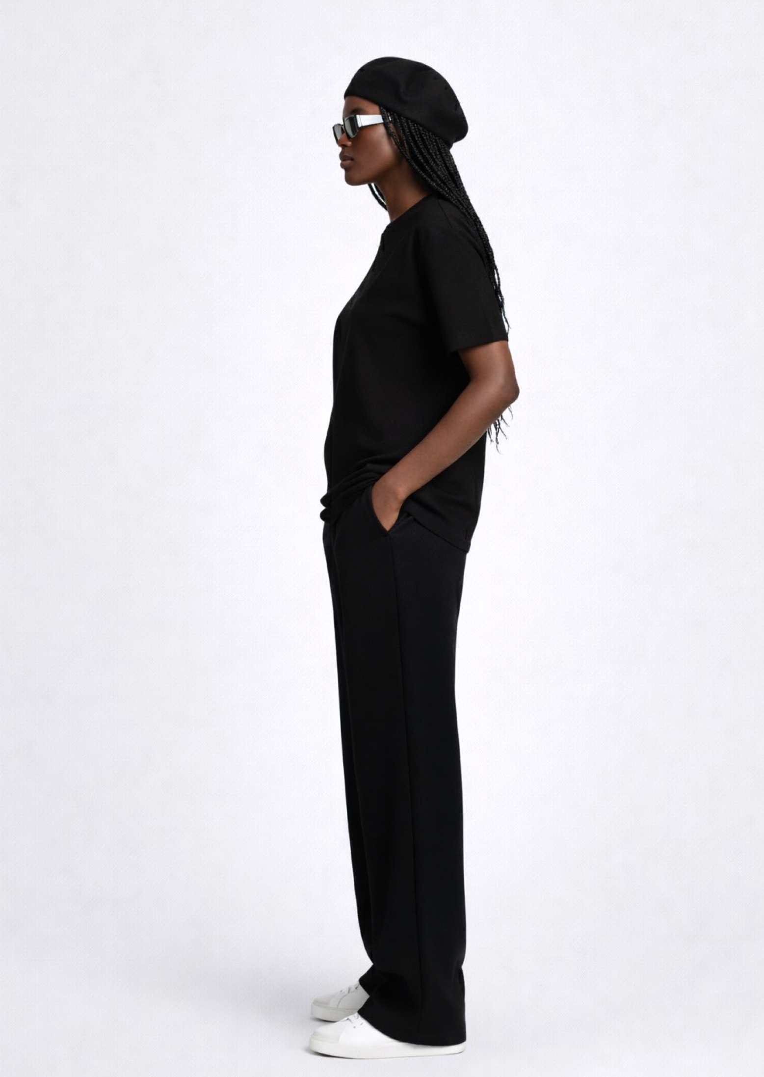 Black woman wearing a black essential Northwind t-shirt with embroidered logo on the chest, Gucci sunglasses, white Adidas Originals and black beret. 