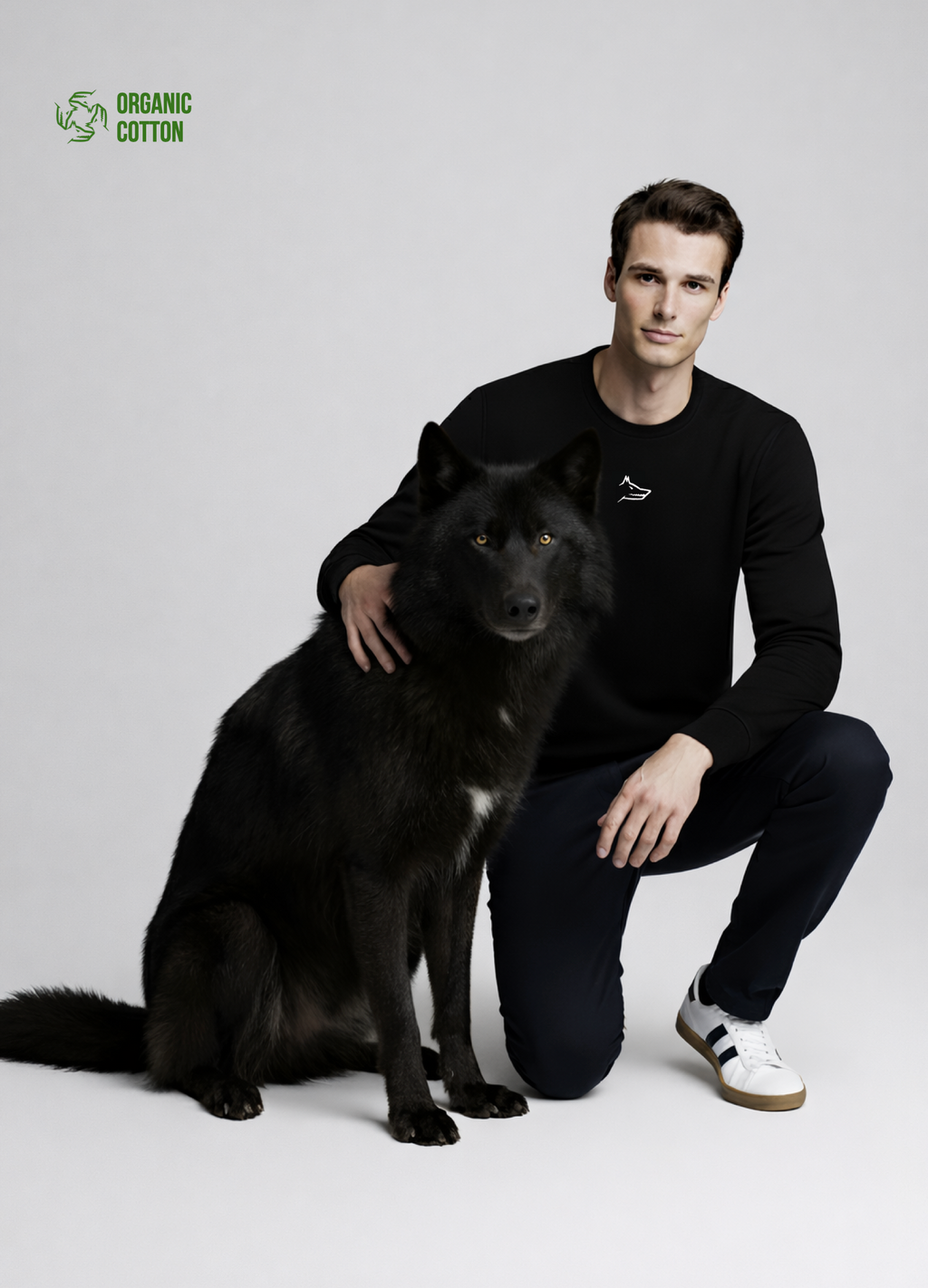 Man wearing a black Northwind organic cotton sweatshirt with white embroidered Northwind wolf logo on the chest giving a pose with a black wolf