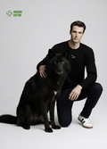 Man wearing a black Northwind organic cotton sweatshirt with white embroidered Northwind wolf logo on the chest giving a pose with a black wolf