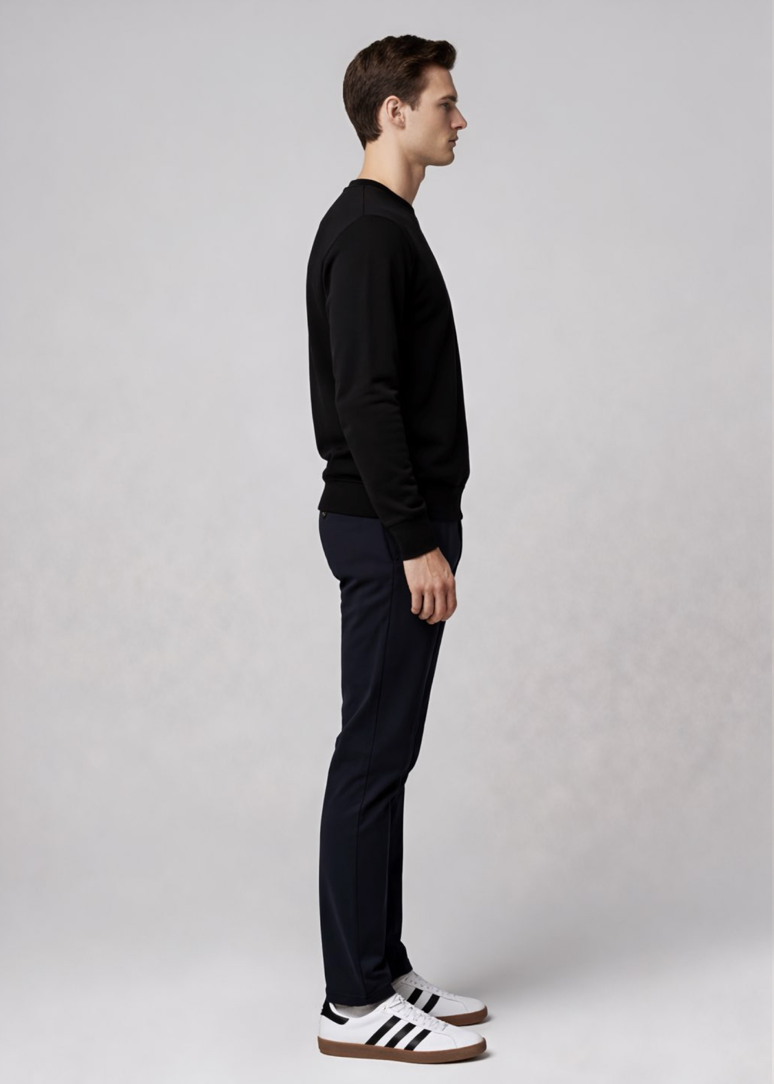 Man wearing a black Northwind sweater and pants with white stripes on shoes against a plain background
