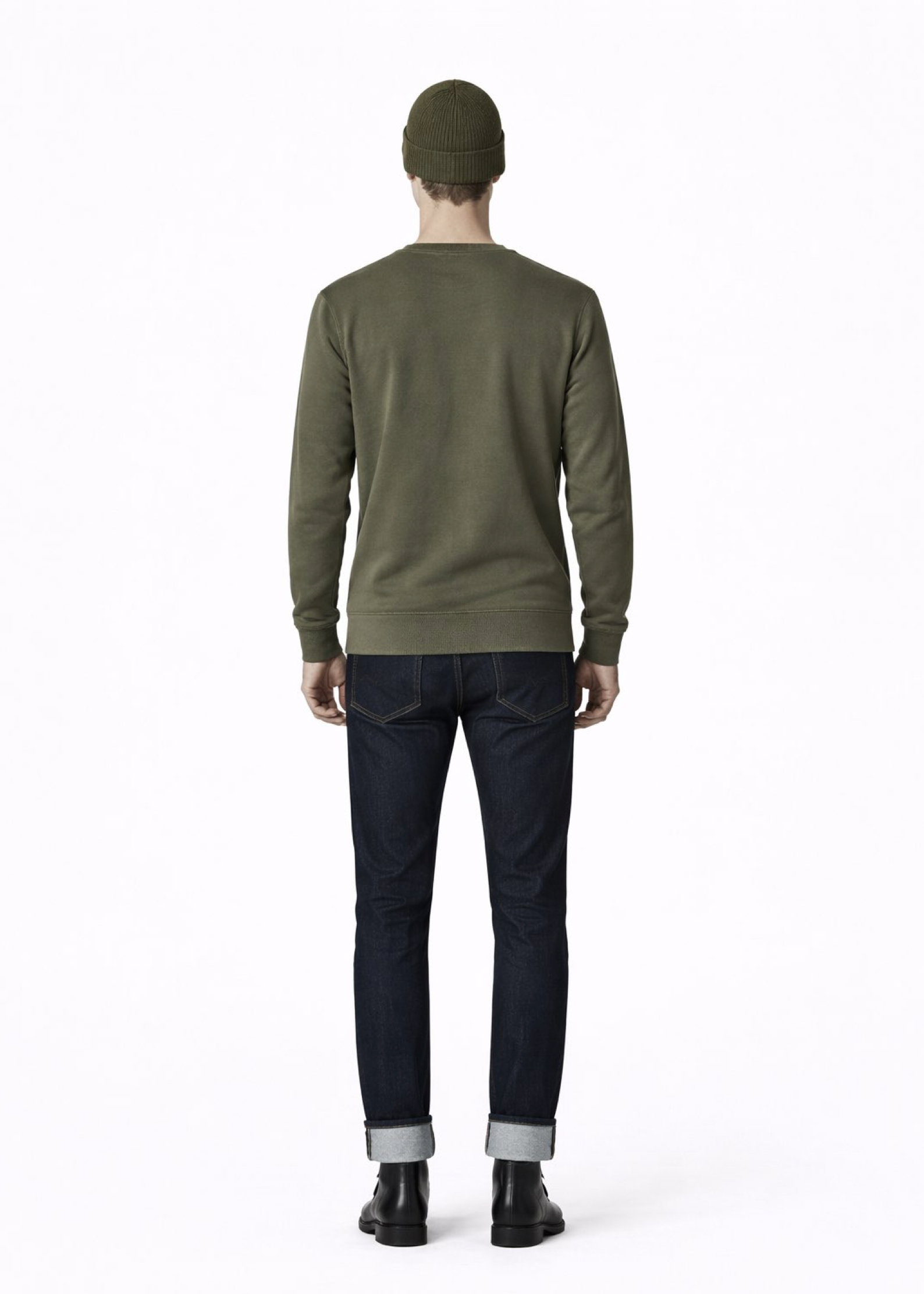 Person wearing a green Northwind sweater and black pants on a gray background