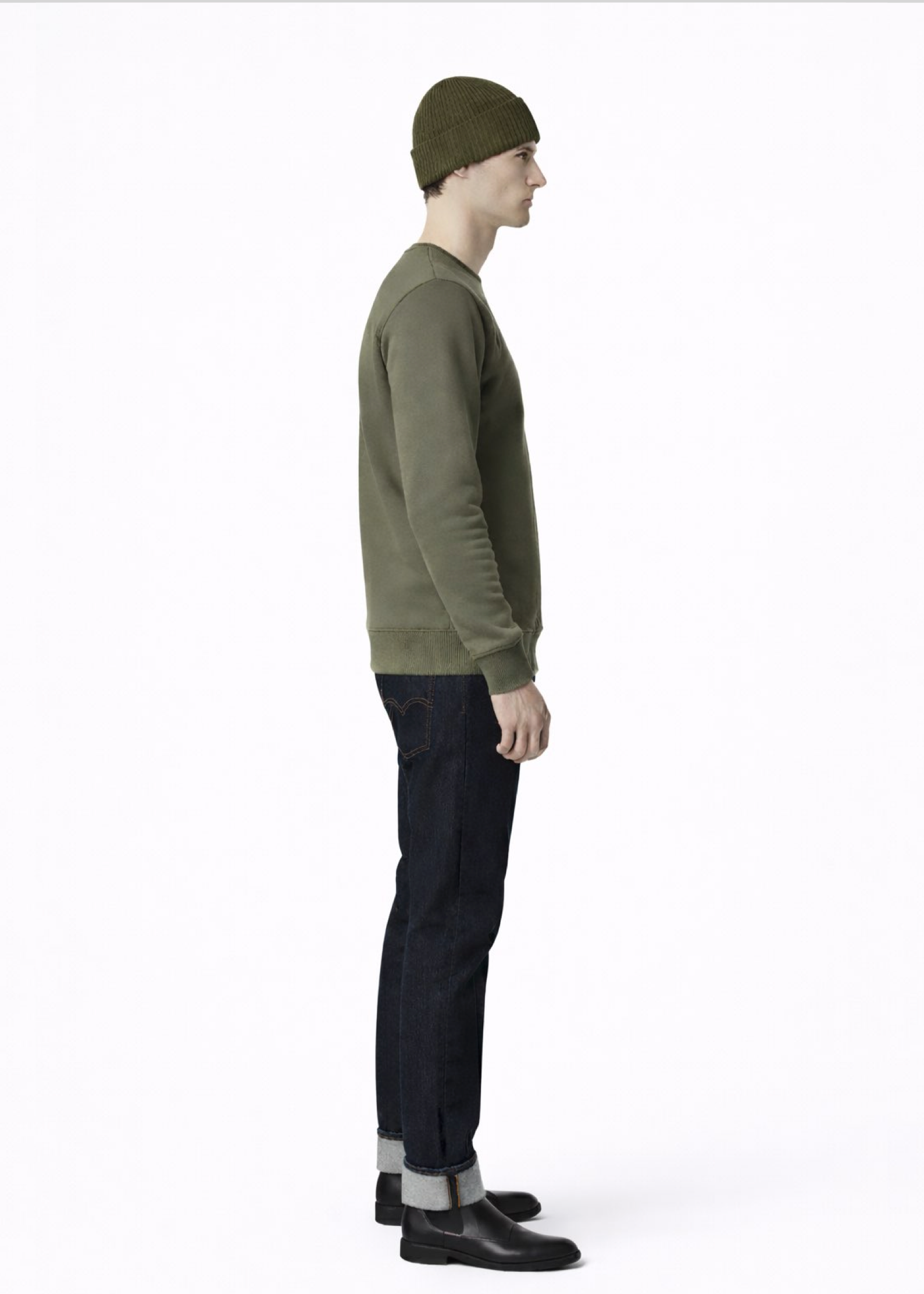 Man wearing a Northwind embroidered wolf logo khaki green sweatshirt and an olive green Northwind organic cotton beanie, and dark pants on a light gray background
