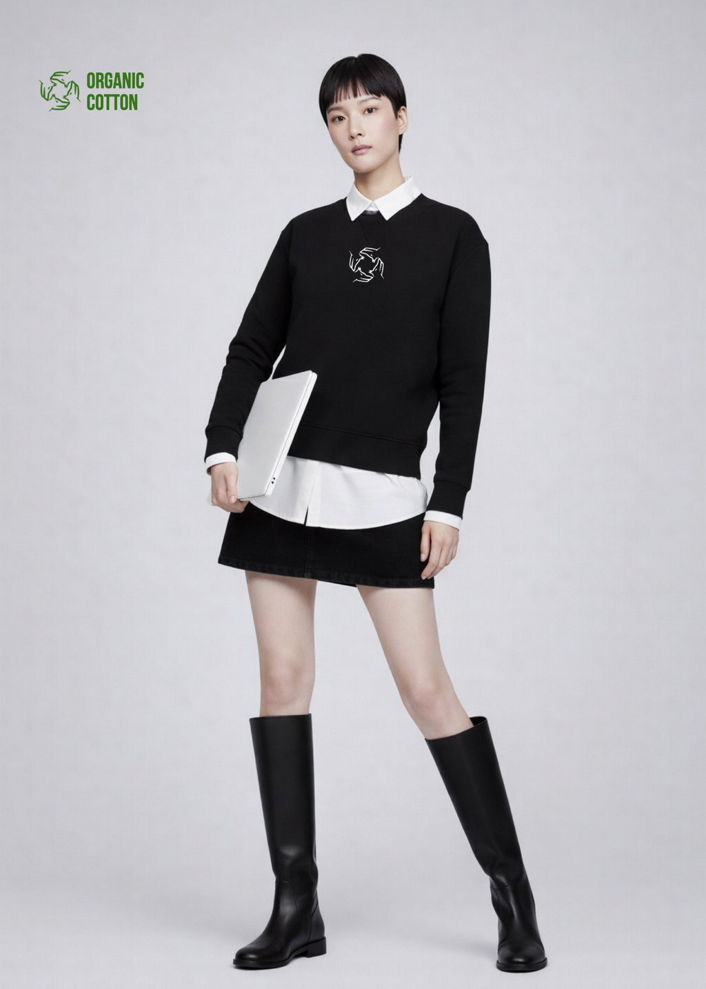 Woman wearing a black Northwind sweatshirt with storm of wolves logo, white shirt, black skirt, and black knee-high boots on a light gray background
