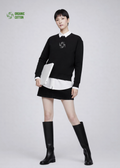 Woman wearing a black Northwind sweatshirt with storm of wolves logo, white shirt, black skirt, and black knee-high boots on a light gray background
