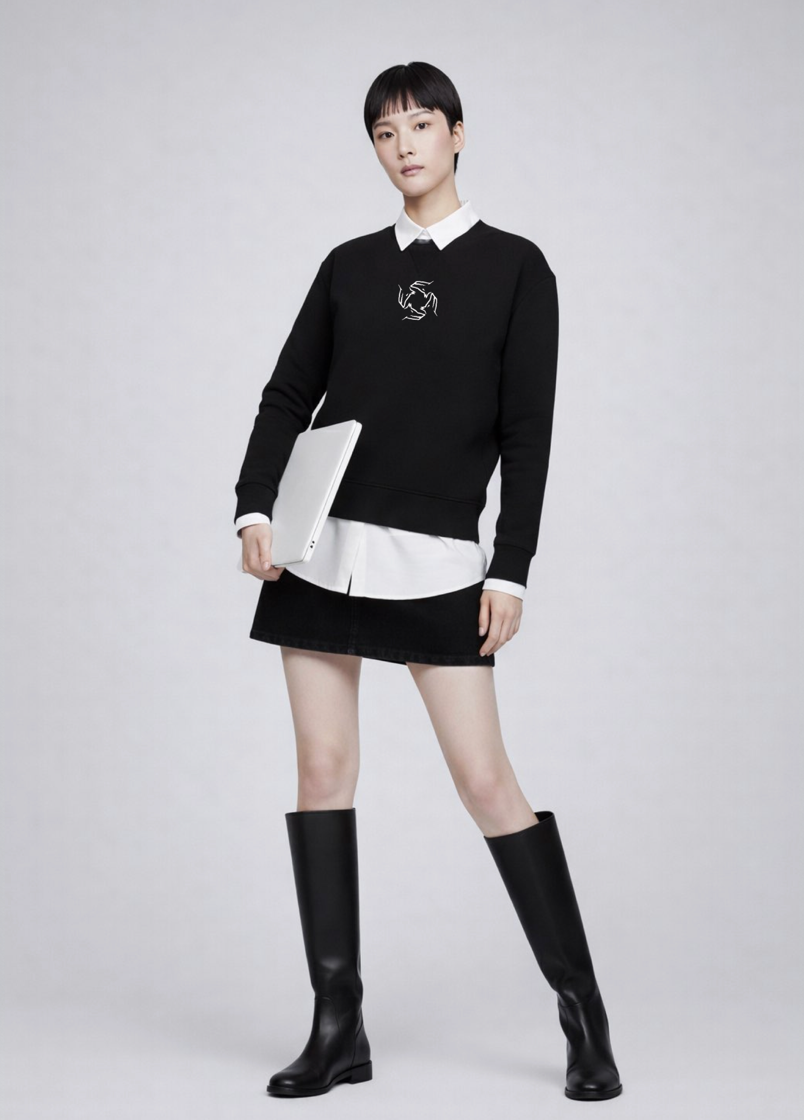Woman wearing a black Northwind sweatshirt with storm of wolves logo, white shirt, black skirt, and black knee-high boots on a light gray background