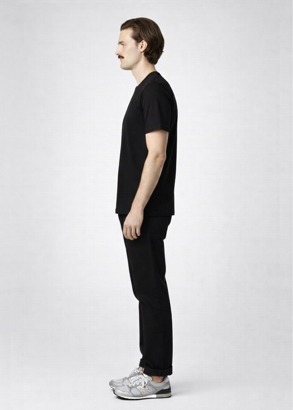 Man wearing a black Northwind storm of wolves t-shirt with embroidered Northwind logo, gray New Balance shoes