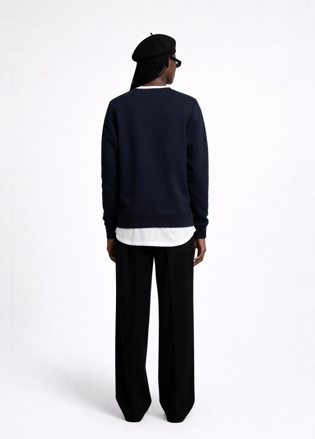 Black woman wearing a french navy blue Northwind sweatshirt black pants, and a black beret on a white background
