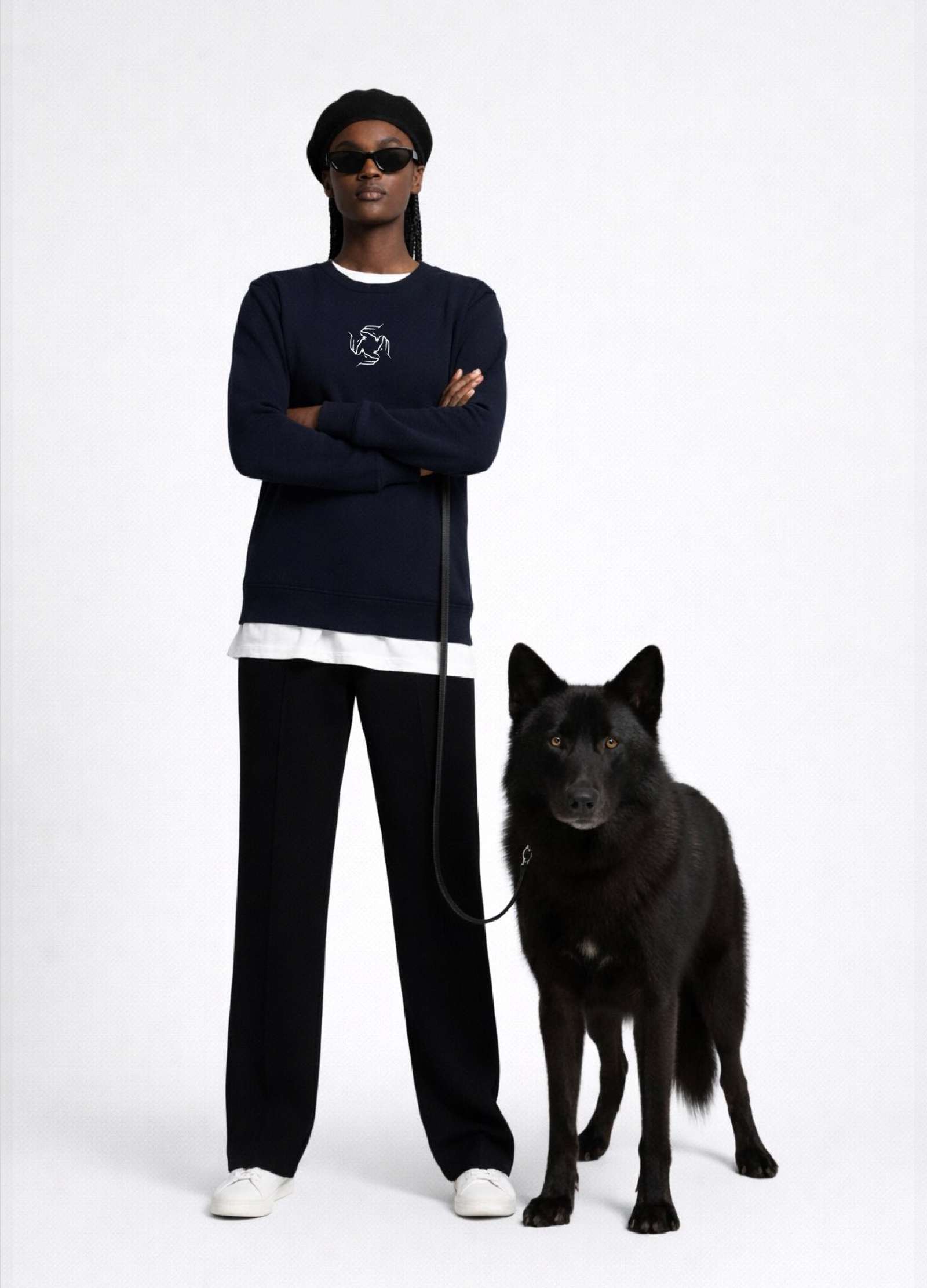 Black woman wearing a french navy blue Northwind sweatshirt with Northwind storm of wolves embroidered logo on the chest, black pants, and a black beret on a white background with a black wolf