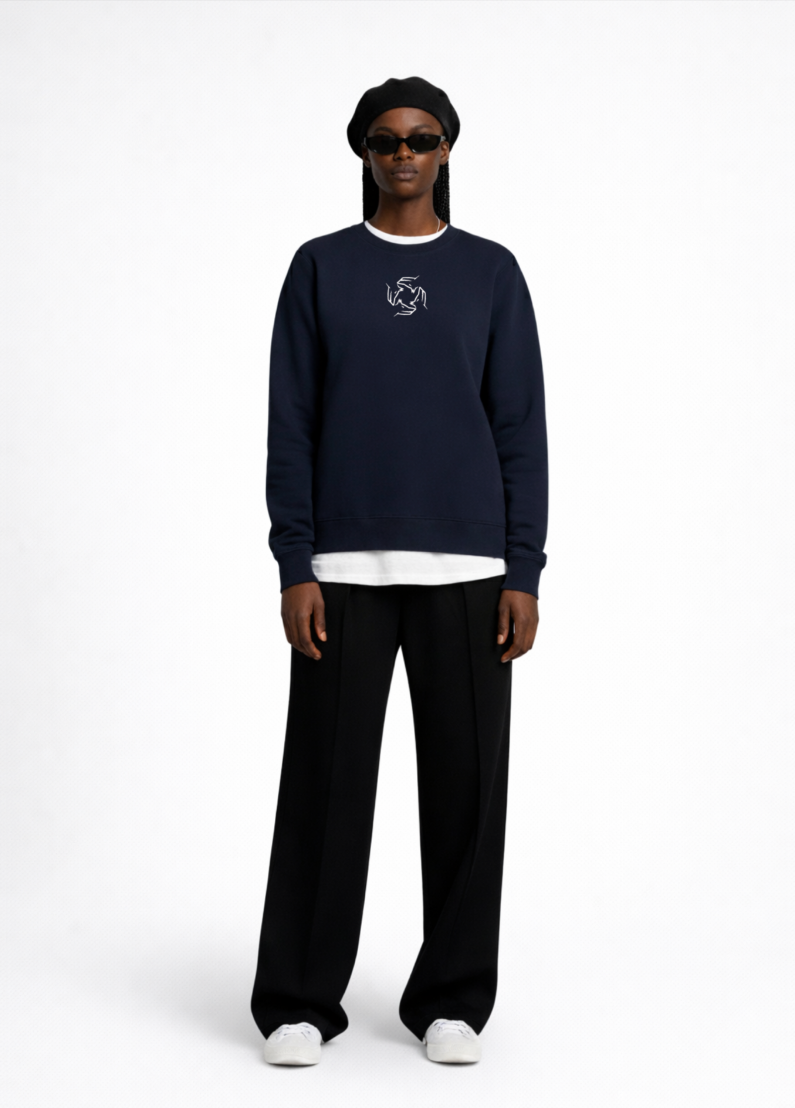 Black woman wearing a french navy blue Northwind sweatshirt with Northwind storm of wolves embroidered logo on the chest, black pants, and a black beret on a white background