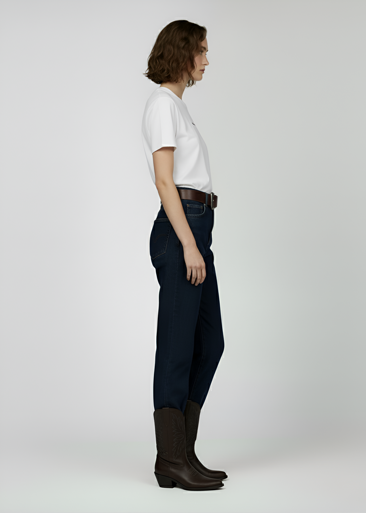 Woman wearing a white Northwind t-shirt, dark jeans, and black boots on a plain background