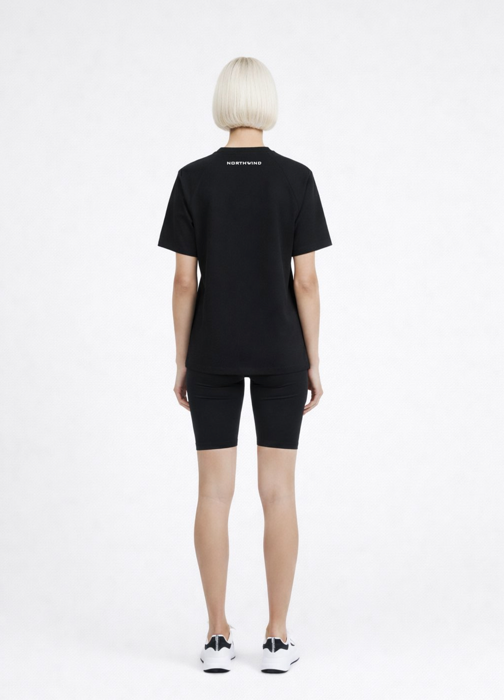 Woman wearing a black Northwind activewear t-shirt with Northwind logo on the back, black shorts and ON Swiss performance running shoes