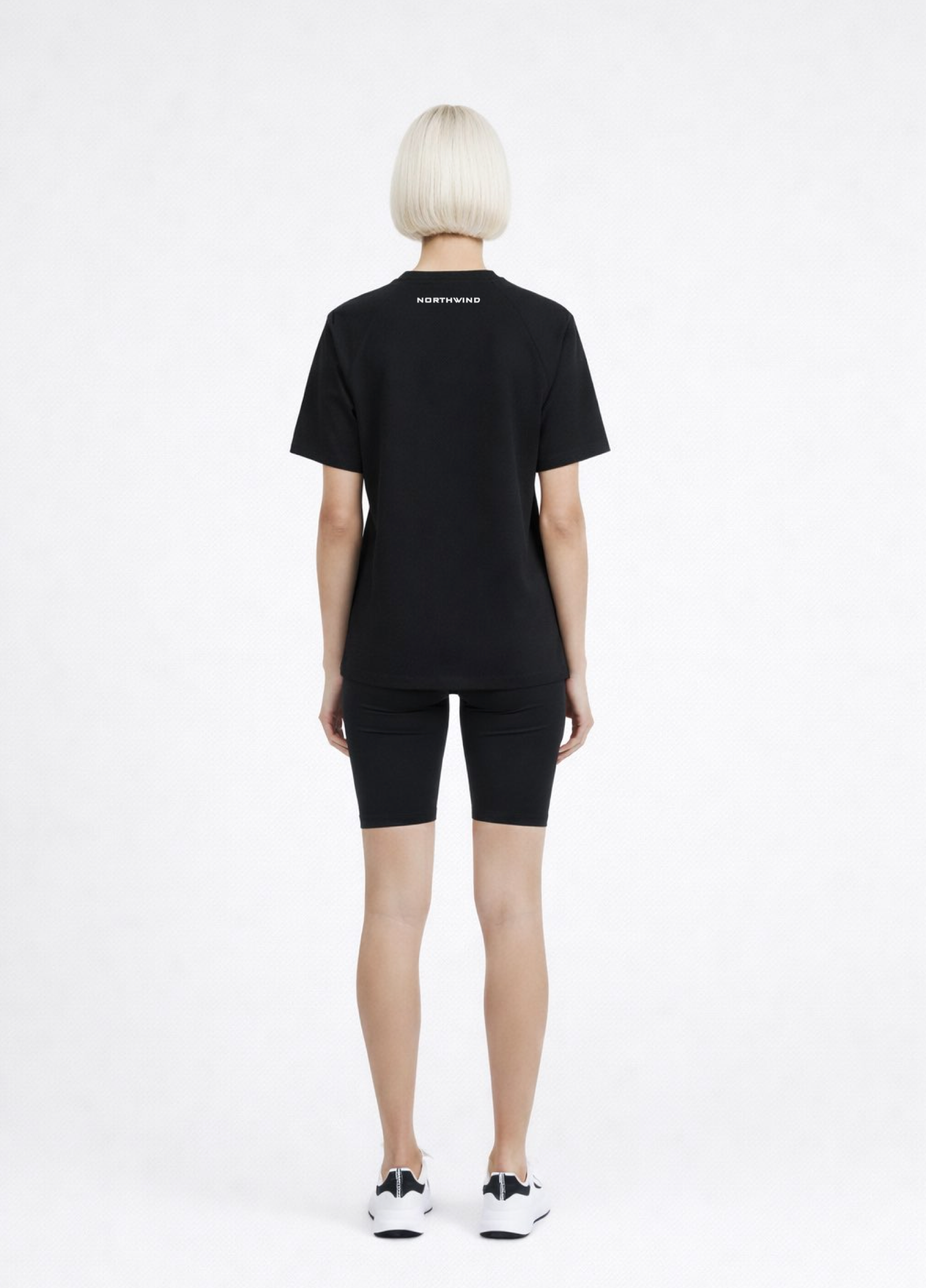 Woman wearing a black Northwind activewear t-shirt with Northwind logo on the back, black shorts and ON Swiss performance running shoes