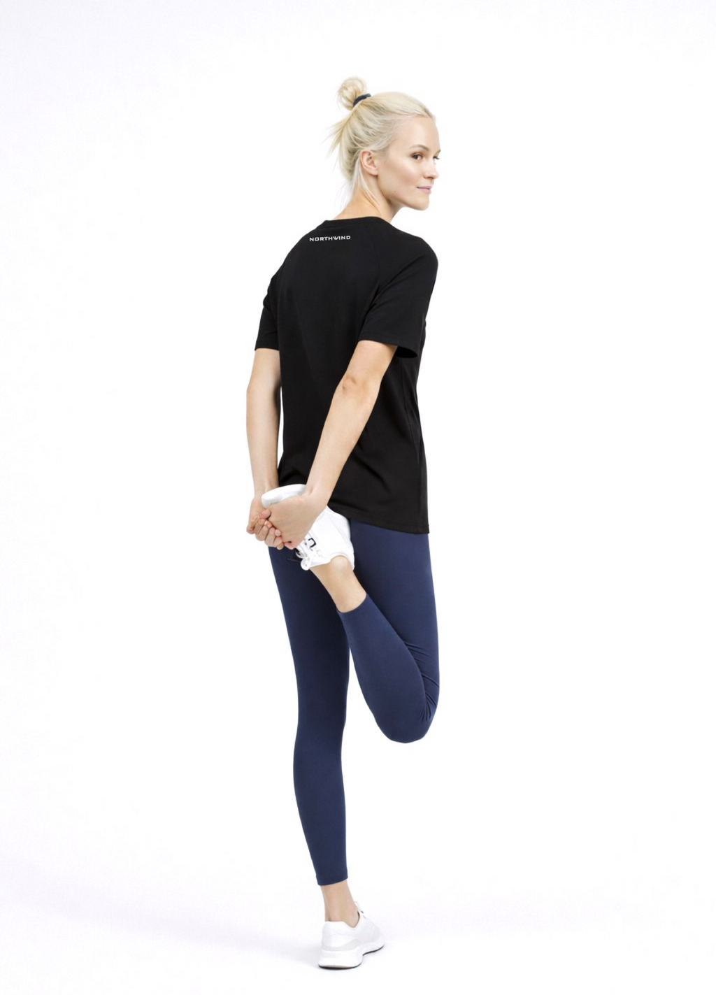 Woman wearing a black Northwind activewear t-shirt with Northwind logo on the back, blue legging and ON Swiss performance running shoes
