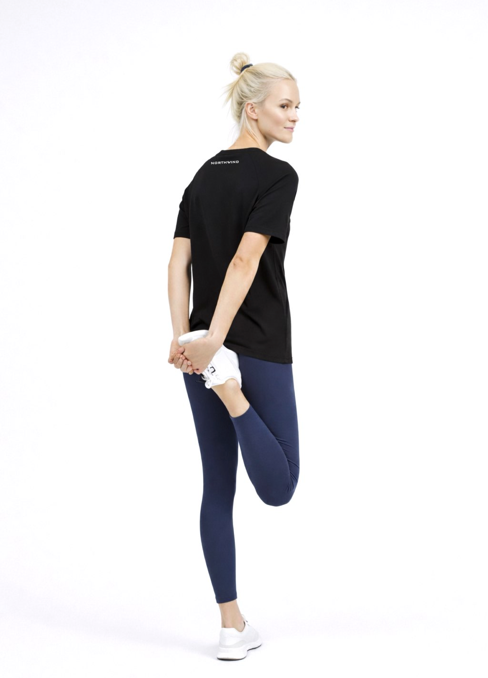 Woman wearing a black Northwind activewear t-shirt with Northwind logo on the back, blue legging and ON Swiss performance running shoes