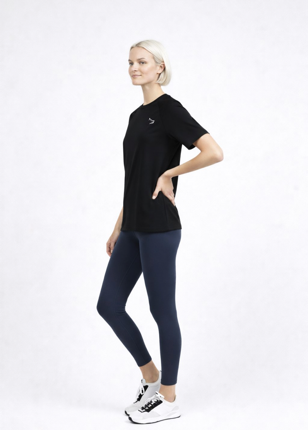 Woman wearing a black Northwind activewear t-shirt with Northwind wolf logo on the chest, navy legging and ON performance running shoes