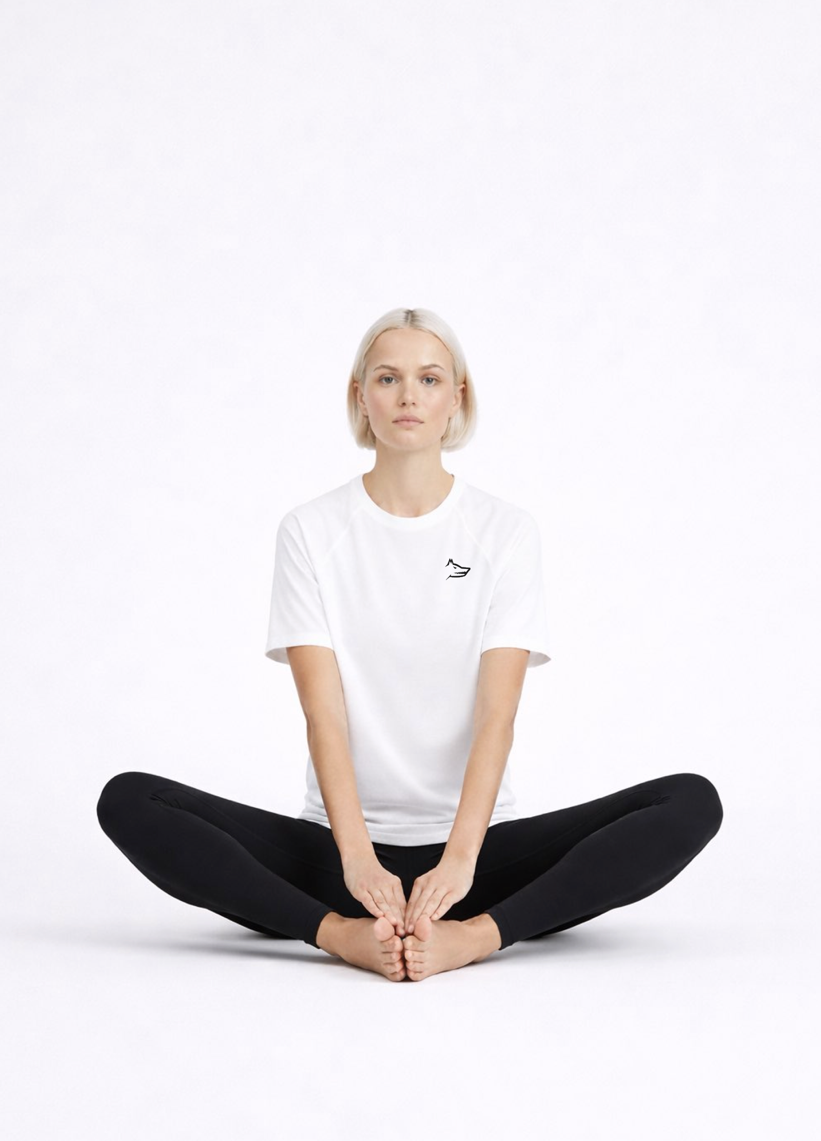 Woman wearing a white Northwind activewear t-shirt with Northwind wolf logo on the chest, sitting in a yoga pose on a white background