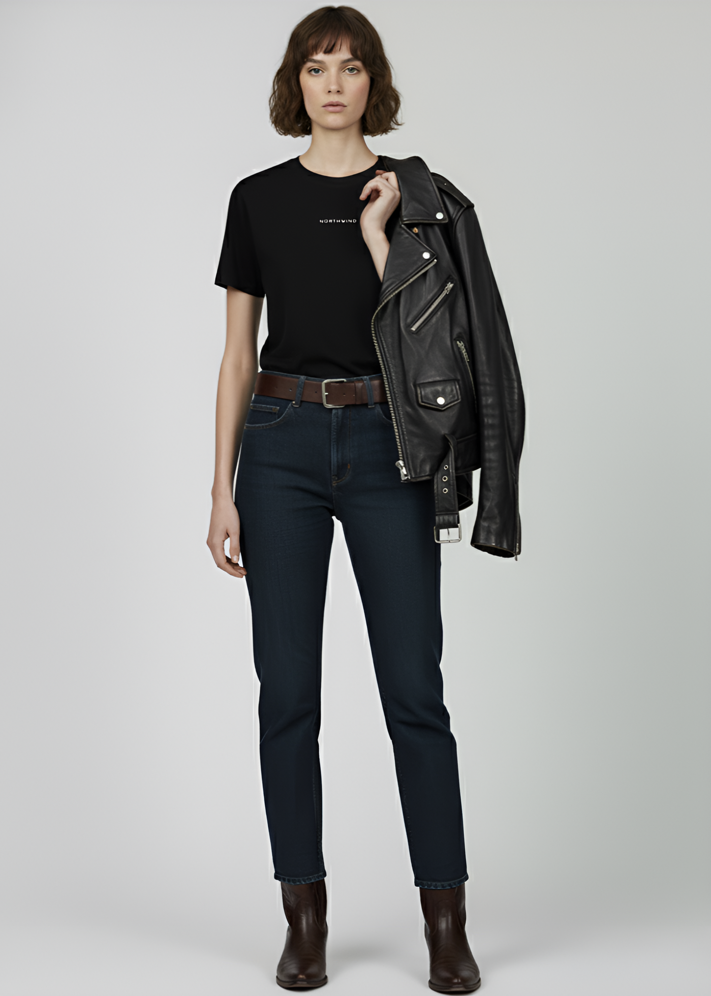 Person wearing a black leather jacket, black Northwind storm of wolves t-shirt, dark jeans, and brown boots on a white background