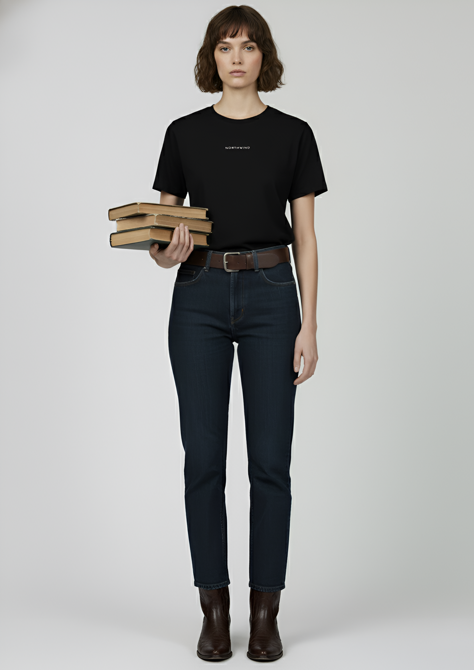 A woman wearing a black Northwind t-shirt and dark jeans holding books on a plain background